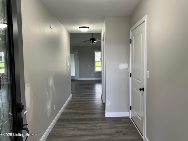 hallway featuring dark wood-style flooring and baseboards