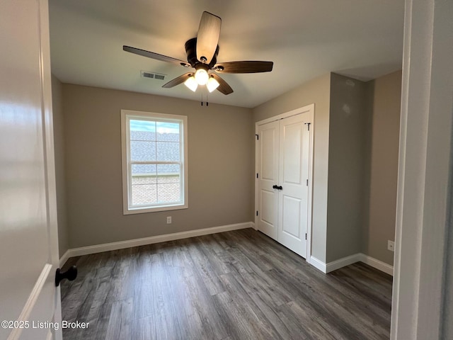 unfurnished bedroom featuring visible vents, ceiling fan, dark wood-style floors, a closet, and baseboards