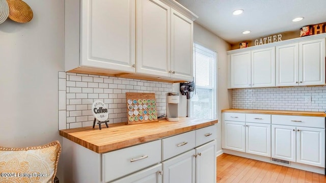 kitchen featuring white cabinetry, butcher block counters, decorative backsplash, and light hardwood / wood-style floors