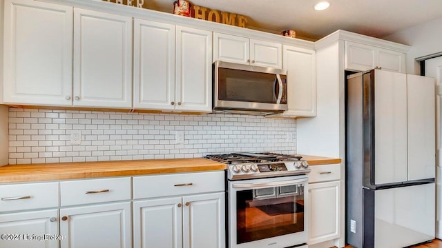 kitchen with appliances with stainless steel finishes, white cabinetry, wood counters, and backsplash