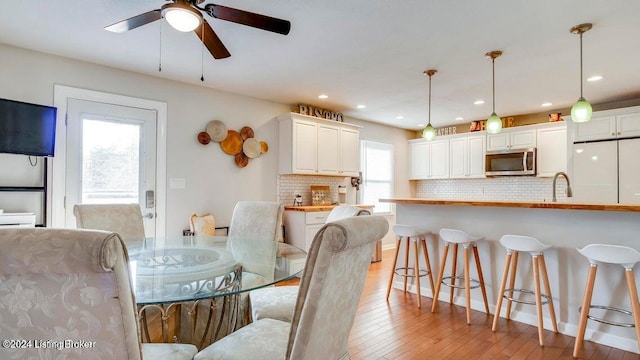 dining area with light hardwood / wood-style floors, ceiling fan, sink, and a wealth of natural light