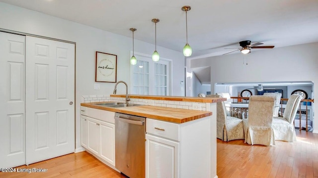 kitchen featuring dishwasher, light wood-type flooring, butcher block counters, hanging light fixtures, and white cabinetry