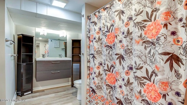 bathroom with toilet, hardwood / wood-style floors, curtained shower, and vanity