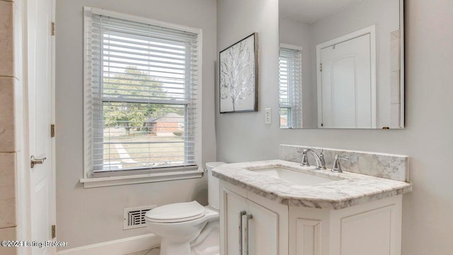 bathroom with vanity, toilet, a healthy amount of sunlight, and tile patterned floors