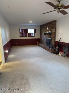 unfurnished living room featuring carpet, a fireplace, and ceiling fan