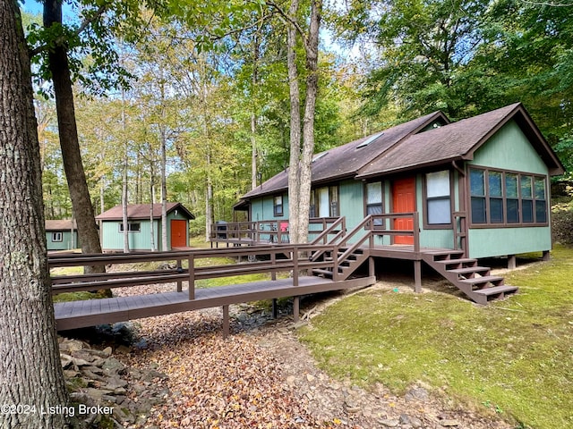 rear view of property with a deck and a lawn