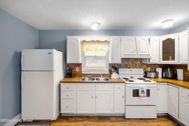 kitchen with decorative backsplash, white appliances, sink, wood-type flooring, and white cabinets