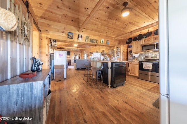 kitchen with wooden walls, stainless steel appliances, light wood-style flooring, and a kitchen bar