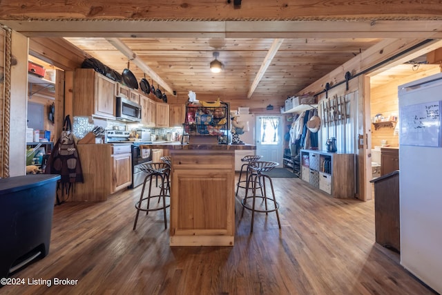 kitchen featuring a kitchen island, dark wood-style flooring, a kitchen bar, a barn door, and stainless steel appliances
