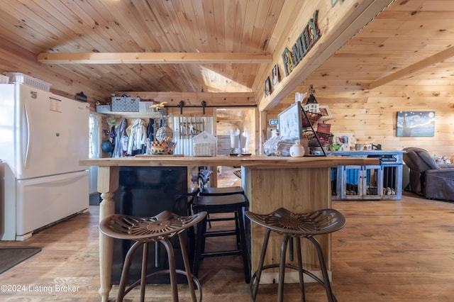 bar with wooden walls, wood ceiling, freestanding refrigerator, and wood finished floors