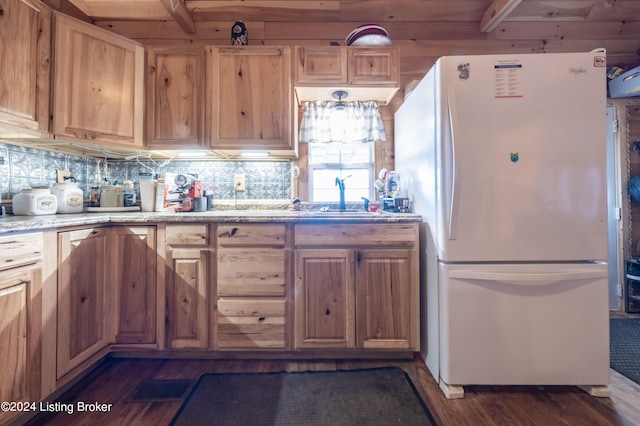 kitchen with freestanding refrigerator, backsplash, dark wood-style floors, and light stone countertops