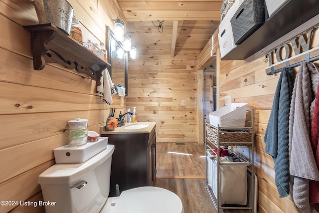 half bathroom featuring wood walls, wood finished floors, wooden ceiling, vanity, and toilet