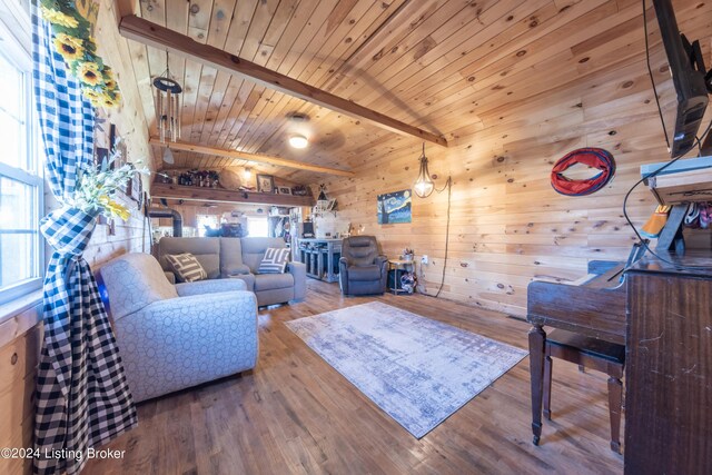 living room featuring vaulted ceiling with beams, wood walls, wood finished floors, and wooden ceiling