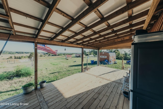 deck featuring a lawn, a rural view, an outbuilding, and a shed