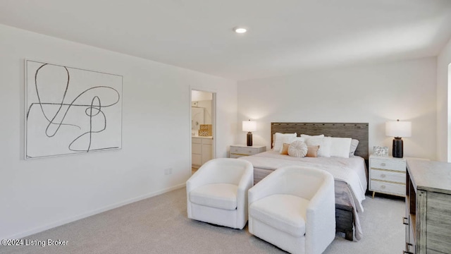 bedroom featuring ensuite bathroom and light colored carpet