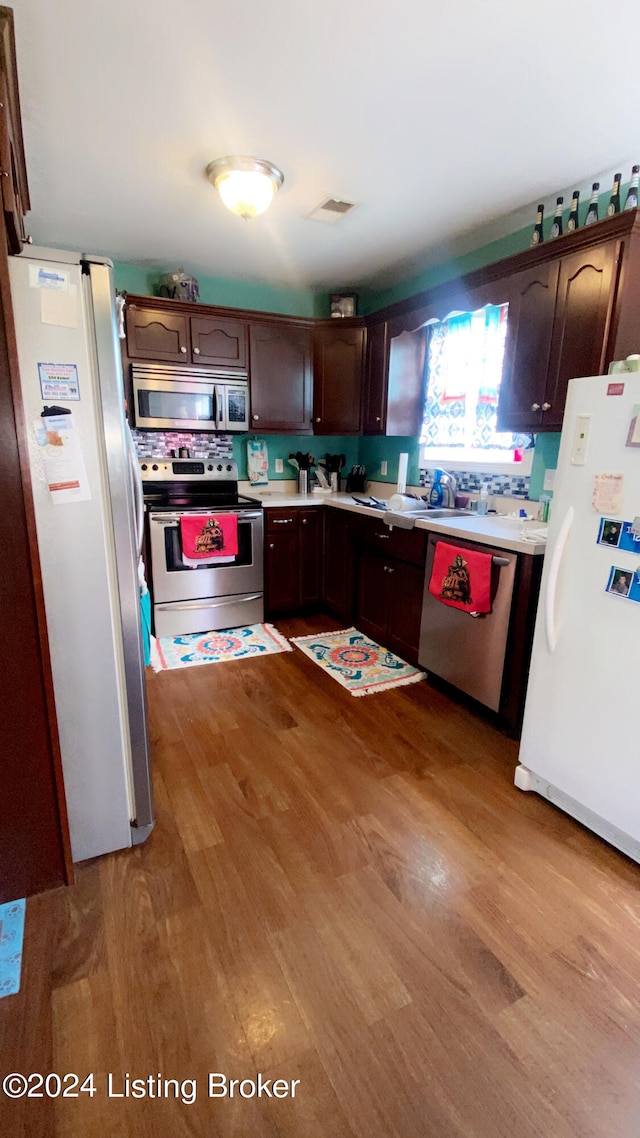 kitchen with appliances with stainless steel finishes, light hardwood / wood-style flooring, and dark brown cabinets