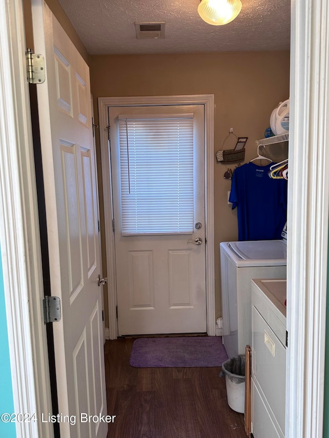 laundry room featuring dark hardwood / wood-style floors, a textured ceiling, and washing machine and clothes dryer