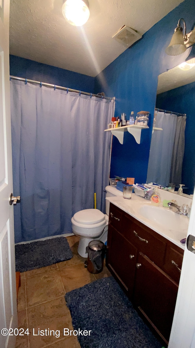 bathroom featuring a textured ceiling, walk in shower, toilet, vanity, and tile patterned flooring