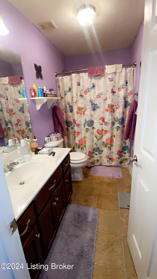 bathroom with tile patterned floors, toilet, vanity, a textured ceiling, and walk in shower