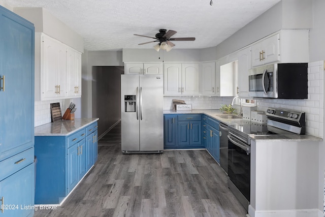 kitchen with white cabinets, appliances with stainless steel finishes, a textured ceiling, blue cabinetry, and sink