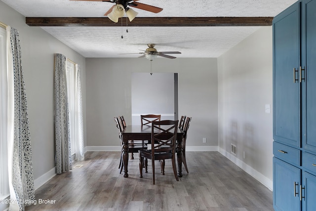 dining area featuring beam ceiling, a textured ceiling, hardwood / wood-style flooring, and ceiling fan