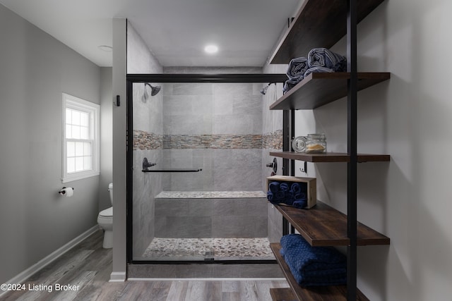 bathroom with toilet, an enclosed shower, and hardwood / wood-style floors