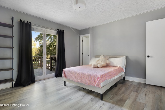 bedroom with a textured ceiling, access to exterior, and light wood-type flooring