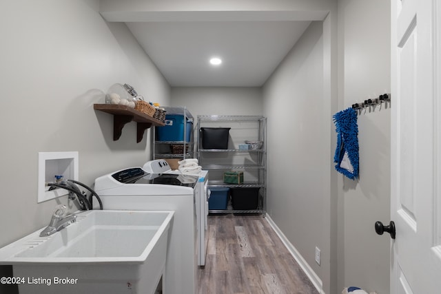 washroom with hardwood / wood-style flooring, sink, and washing machine and clothes dryer