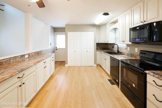 kitchen featuring sink, light stone counters, white cabinets, black appliances, and light wood-type flooring