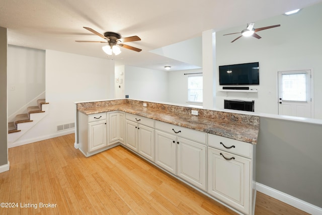 kitchen featuring a wealth of natural light, light hardwood / wood-style flooring, white cabinets, and stone countertops