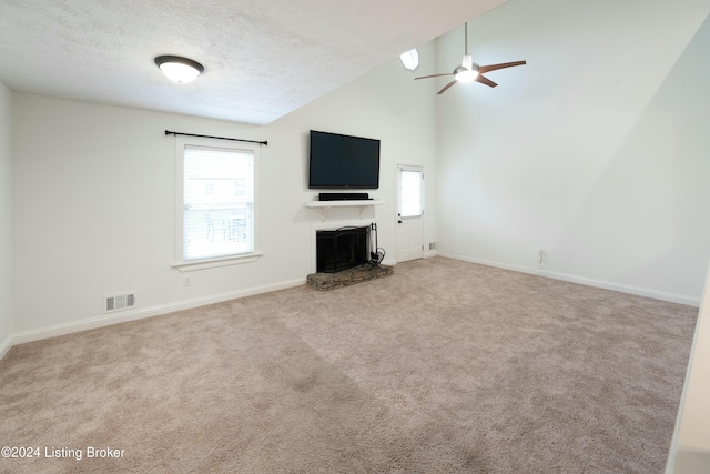 unfurnished living room featuring a textured ceiling, light colored carpet, high vaulted ceiling, and ceiling fan