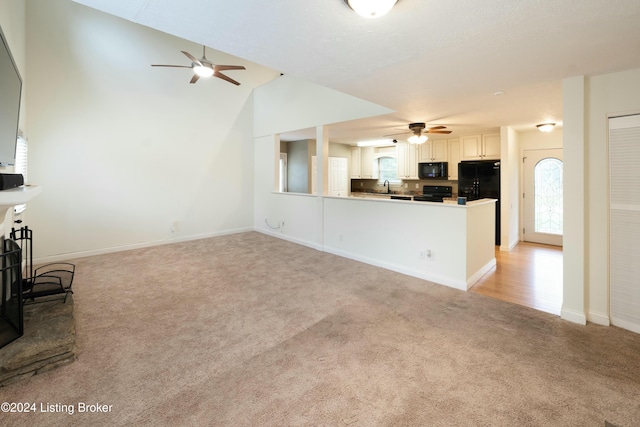 unfurnished living room featuring light colored carpet, a healthy amount of sunlight, and lofted ceiling