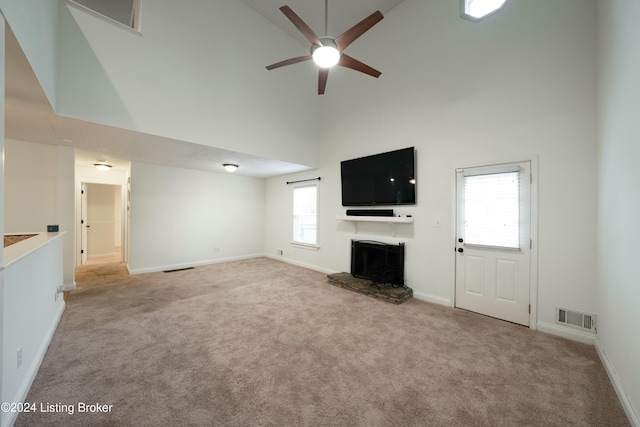 unfurnished living room featuring plenty of natural light, carpet floors, and a high ceiling