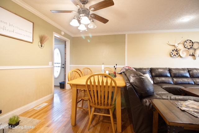 dining room featuring visible vents, ornamental molding, ceiling fan, wood finished floors, and baseboards