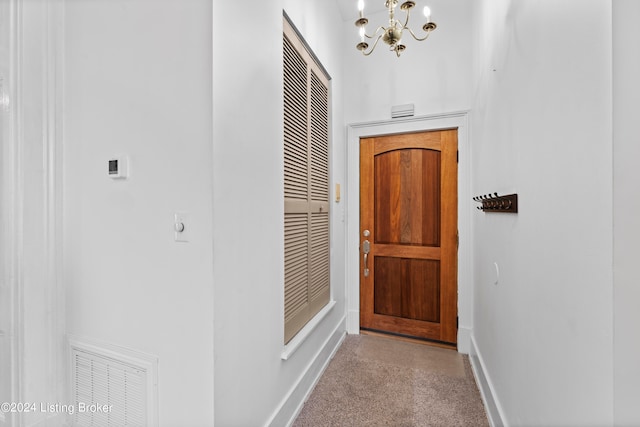 hallway with light carpet and a notable chandelier