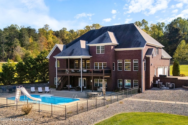 rear view of house with a patio, a fenced in pool, and a balcony