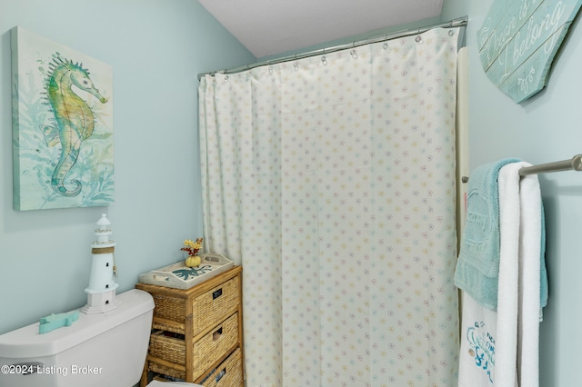 bathroom featuring toilet and curtained shower