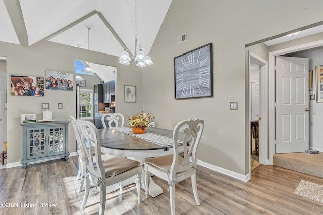 dining room with a chandelier, wood-type flooring, and high vaulted ceiling