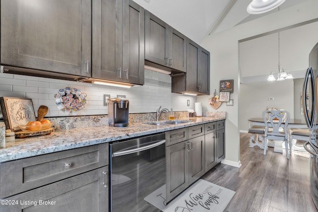 kitchen featuring dishwasher, lofted ceiling, decorative light fixtures, light stone counters, and hardwood / wood-style flooring