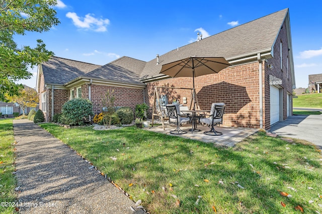 rear view of house with a garage, a yard, and a patio