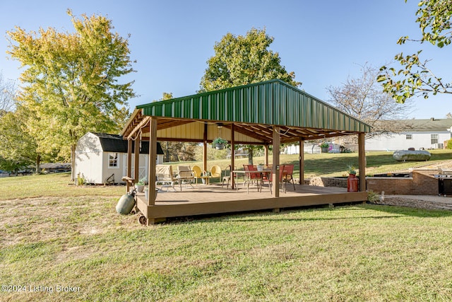 view of community featuring a wooden deck, a gazebo, a storage unit, and a yard