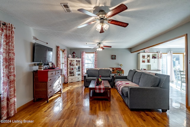 living room with a textured ceiling, hardwood / wood-style flooring, and ceiling fan