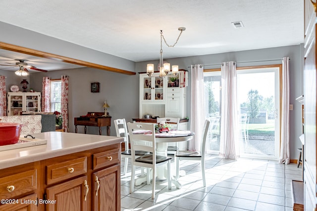 tiled dining space featuring a textured ceiling and ceiling fan with notable chandelier