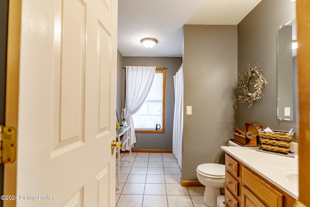 bathroom featuring vanity, a textured ceiling, toilet, and tile patterned flooring