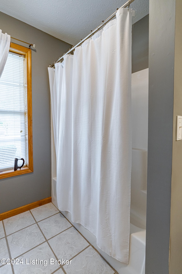 bathroom featuring tile patterned floors, shower / bath combination with curtain, and a textured ceiling