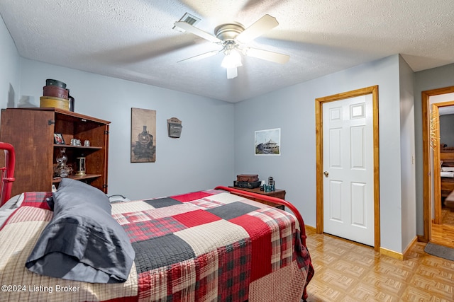 bedroom featuring ceiling fan, light parquet flooring, and a textured ceiling