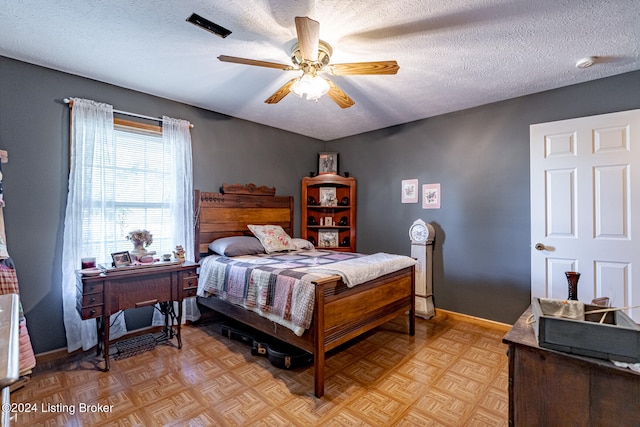 bedroom featuring ceiling fan, light parquet flooring, and a textured ceiling