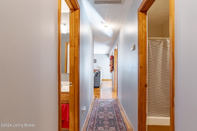 hall featuring hardwood / wood-style flooring, a textured ceiling, and sink