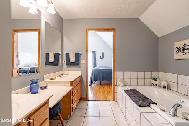 bathroom with vanity, a textured ceiling, a bath, and vaulted ceiling