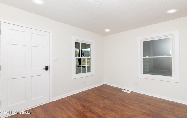 unfurnished room featuring a textured ceiling and dark hardwood / wood-style floors